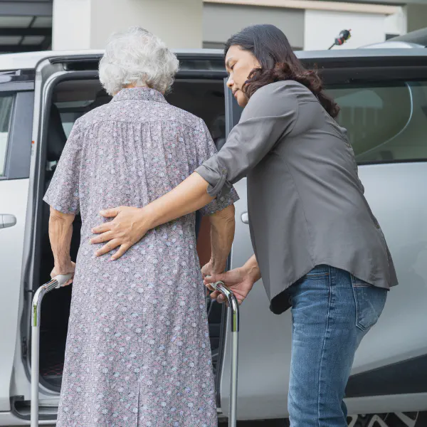 Aide helping elderly women into the car