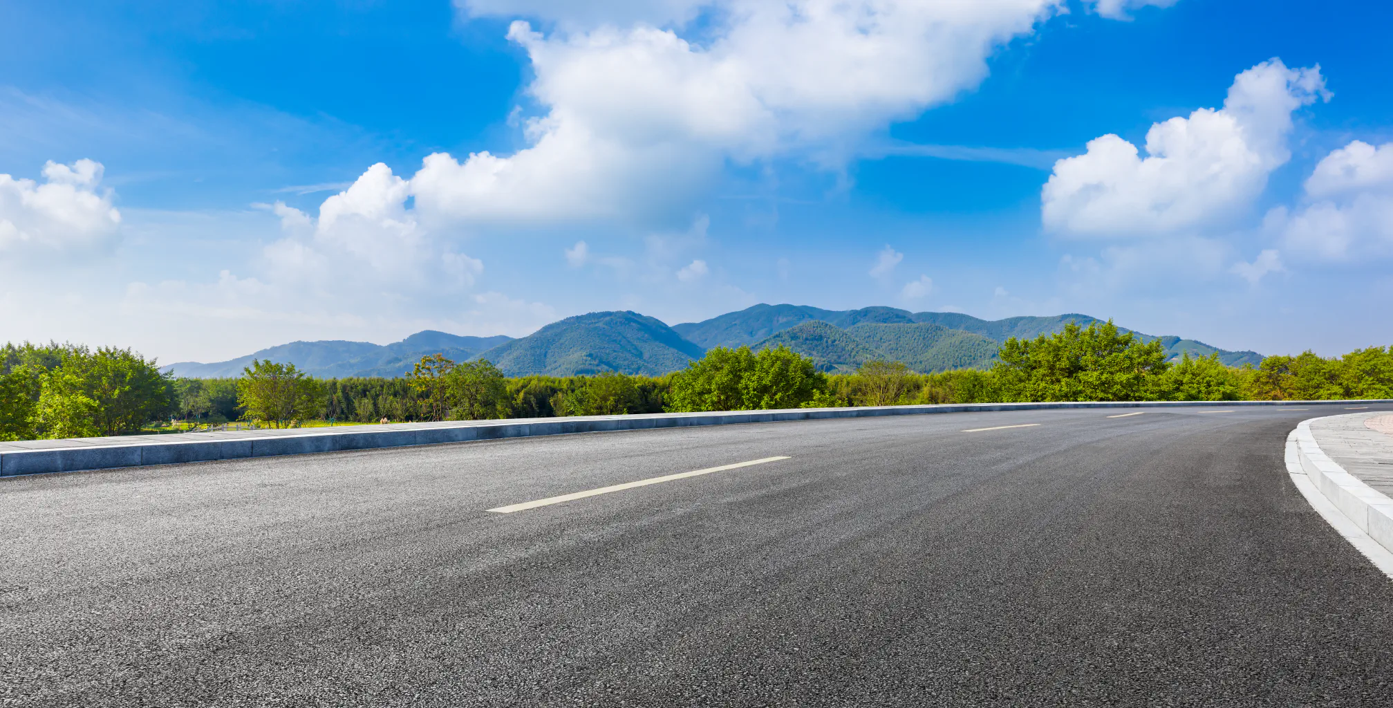 A country road and green mountains in the summer.
